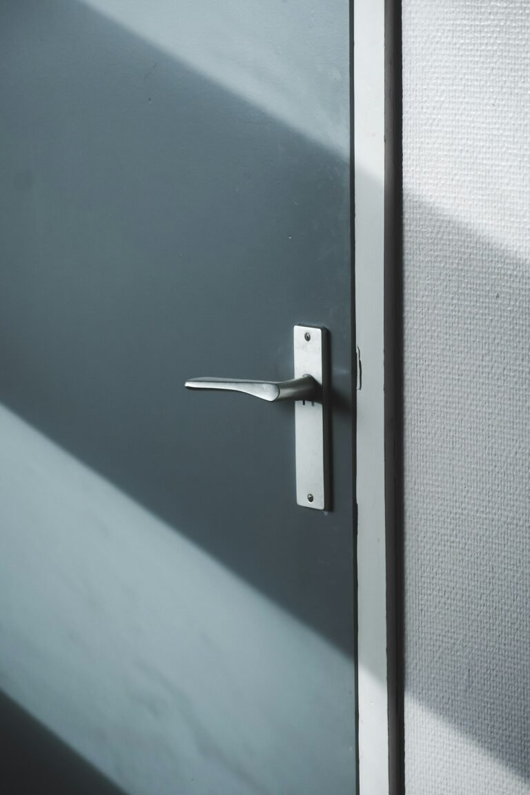 Zilveren deurklink met beslag op een grijze deur