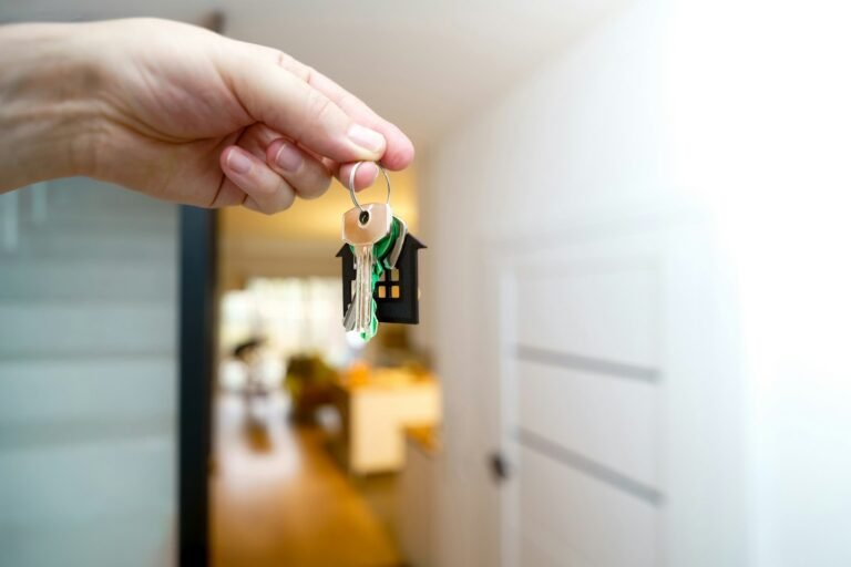 Hand met huissleutels voor de ingang van een woning